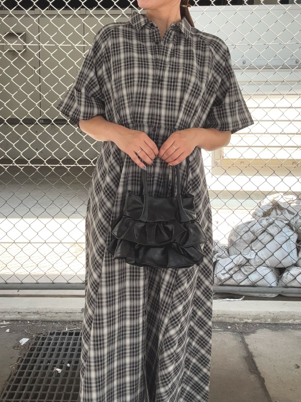 ブラック系のワンピース、ブラウン系のローファー、ブラック系のハンドバッグを着用したレディースの夏コーディネートの5枚目の写真