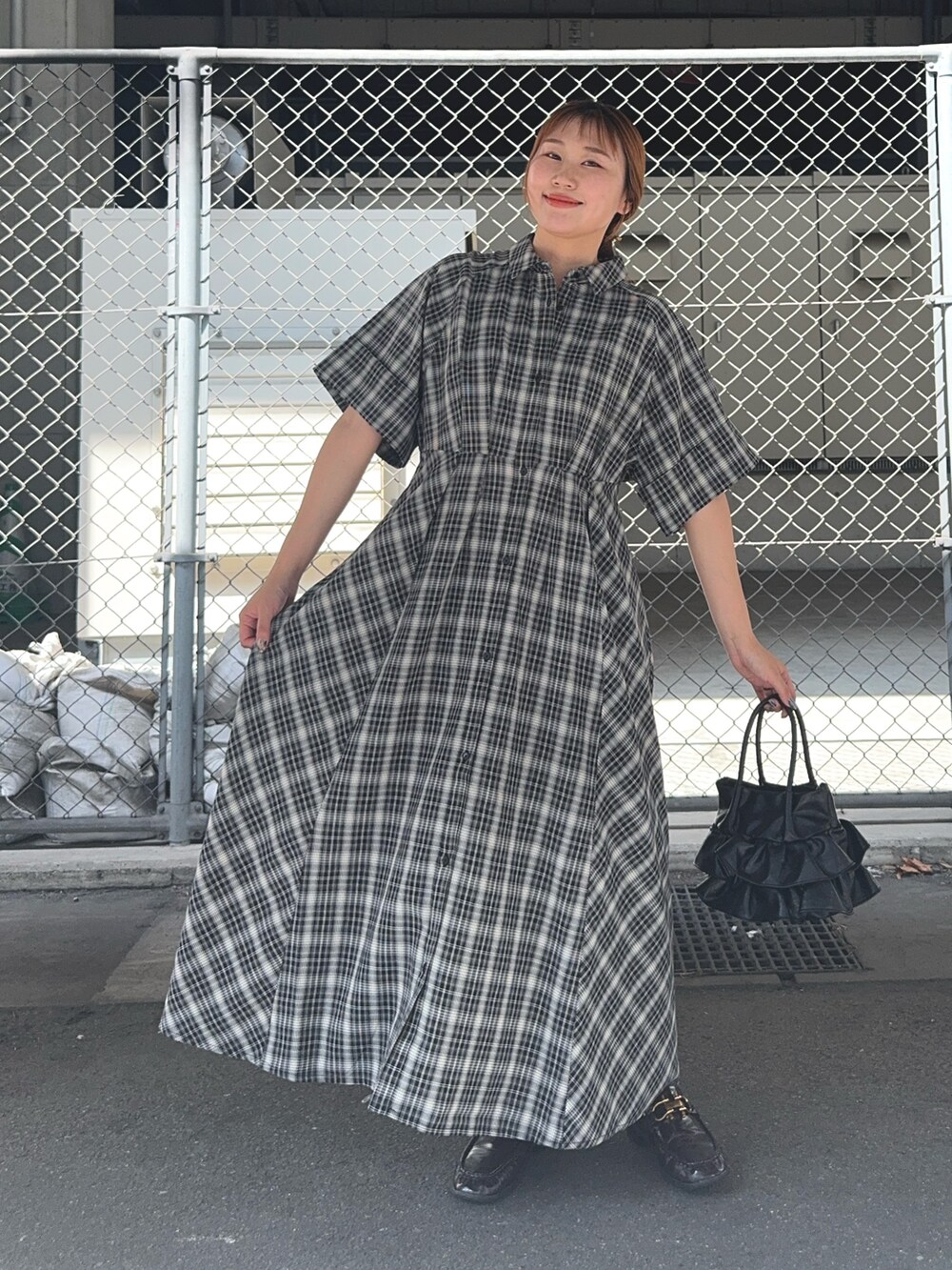 ブラック系のワンピース、ブラウン系のローファー、ブラック系のハンドバッグを着用したレディースの夏コーディネートの2枚目の写真