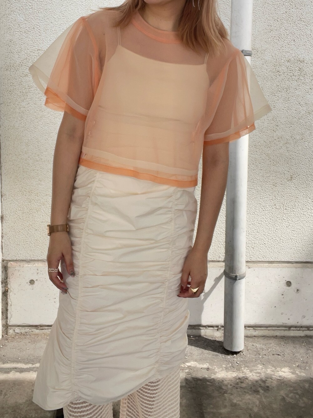 オレンジ系のTシャツ/カットソー、ホワイト系のその他パンツ、その他のピアス（両耳用）を着用したレディースの春コーディネートの4枚目の写真