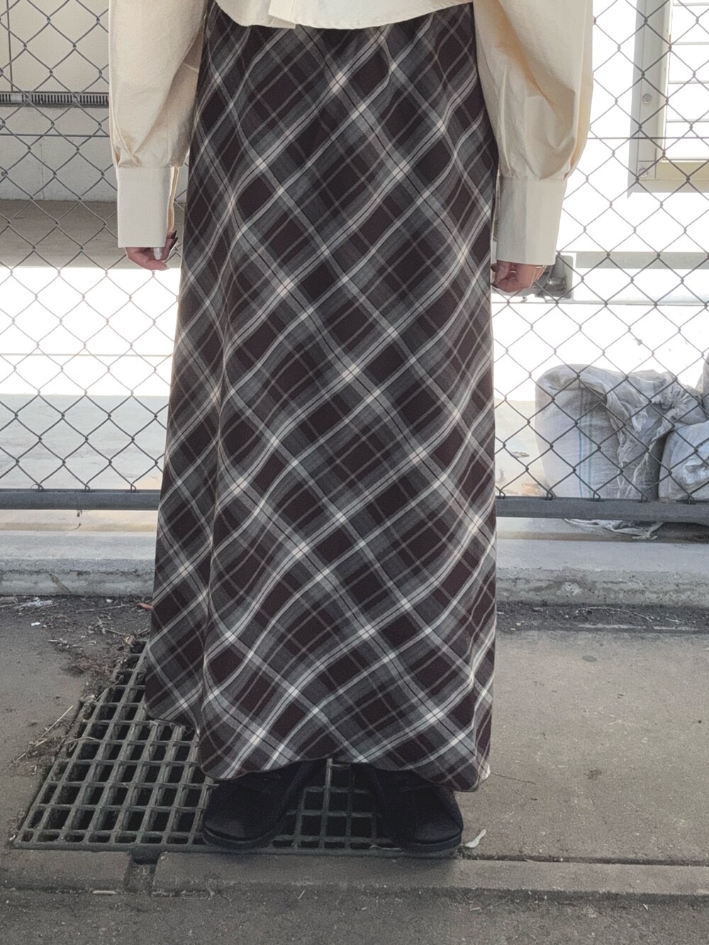 ブラウン系のスカート、ベージュ系のシャツ/ブラウス、ブラック系のスニーカーを着用したレディースの秋コーディネートの6枚目の写真