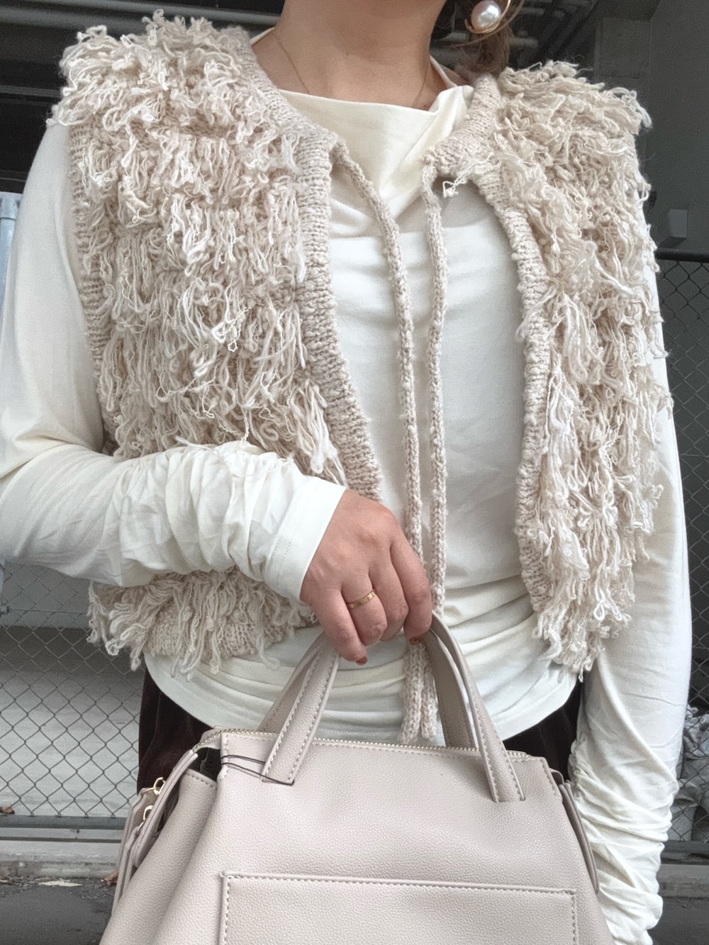 ブラウン系のスカート、ベージュ系のベスト、ホワイト系のTシャツ/カットソーを着用したレディースの秋コーディネートの4枚目の写真