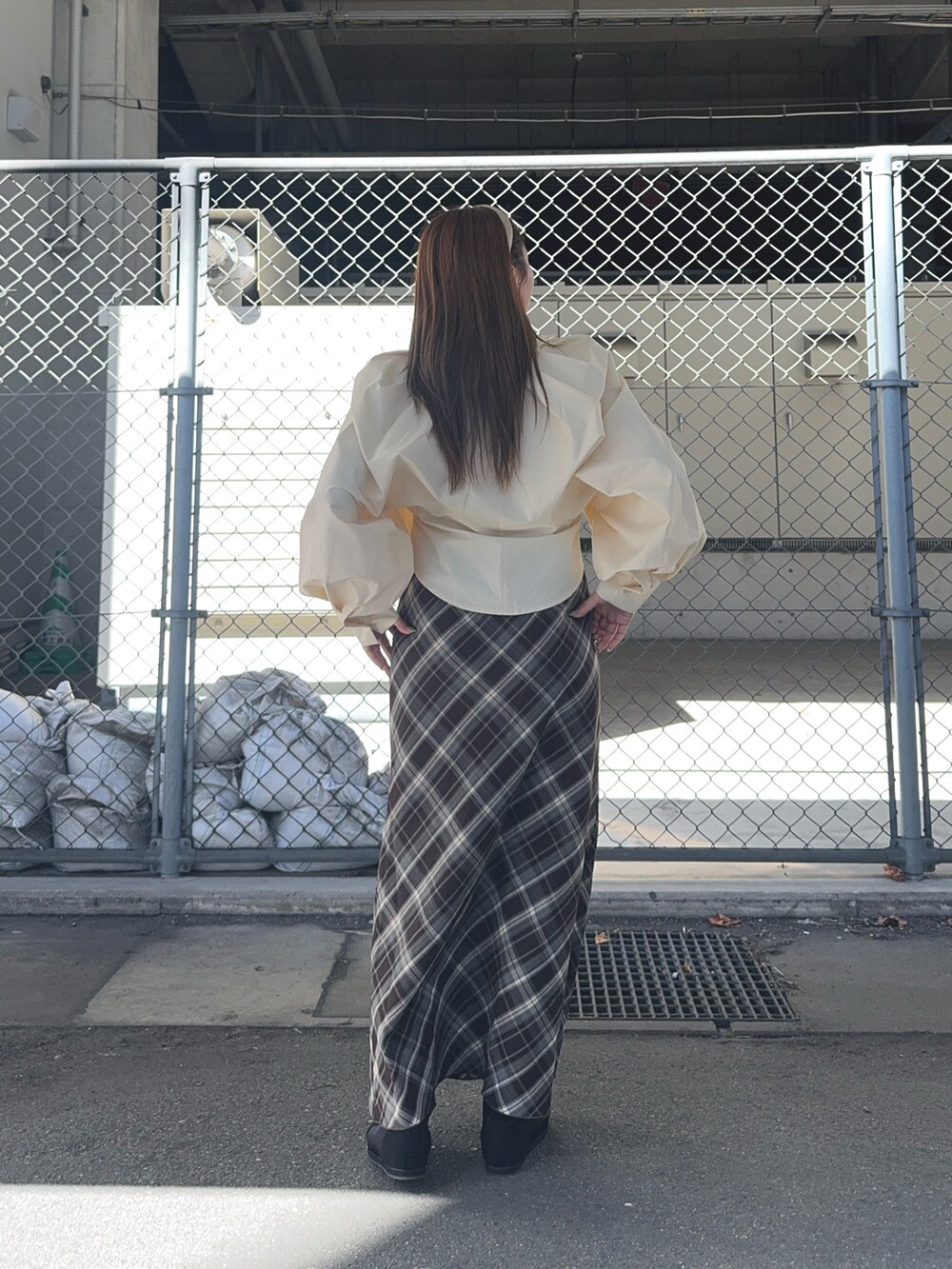 ブラウン系のスカート、ベージュ系のシャツ/ブラウス、ブラック系のスニーカーを着用したレディースの秋コーディネートの4枚目の写真