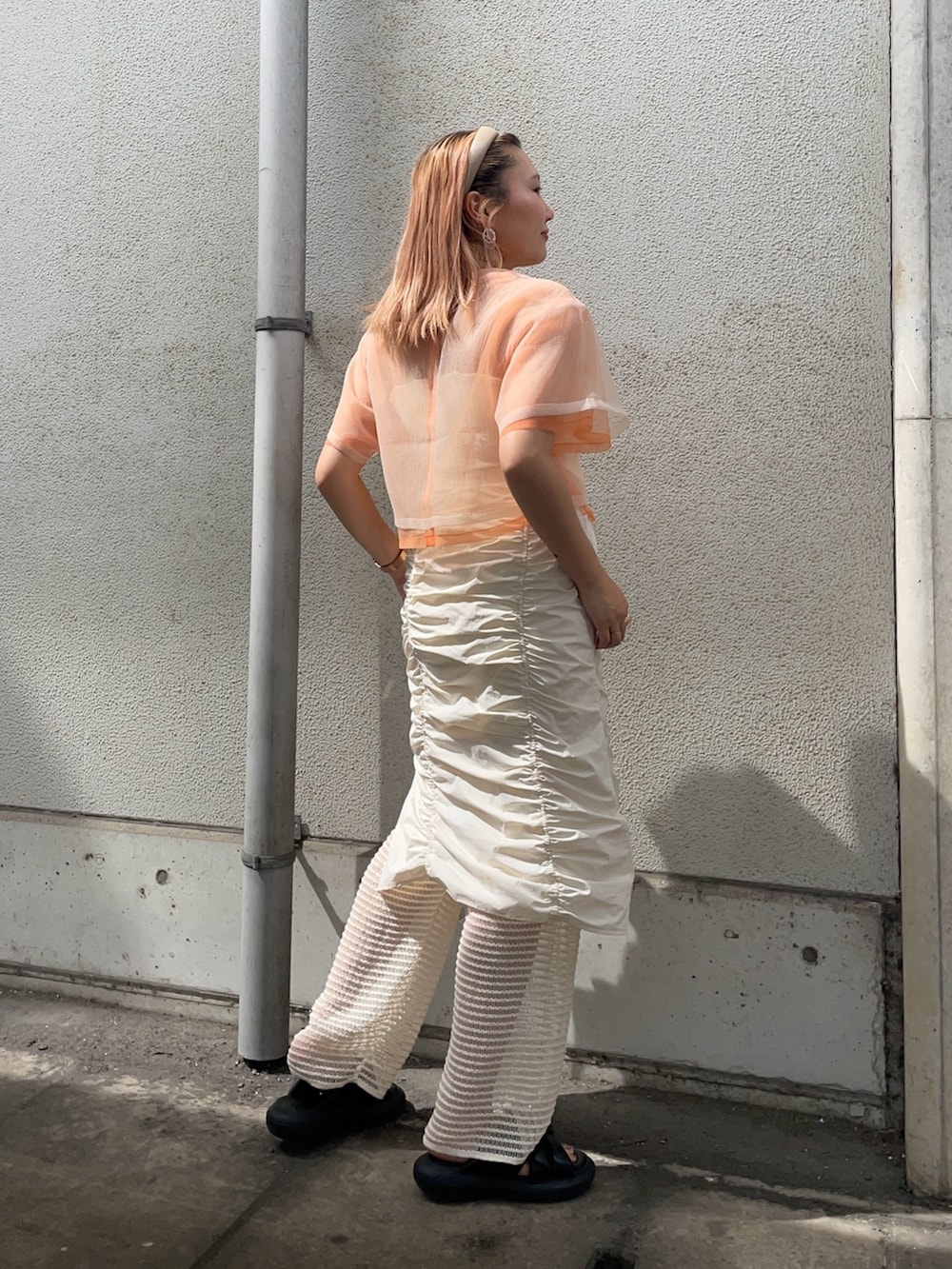 オレンジ系のTシャツ/カットソー、ホワイト系のその他パンツ、その他のピアス（両耳用）を着用したレディースの春コーディネートの2枚目の写真