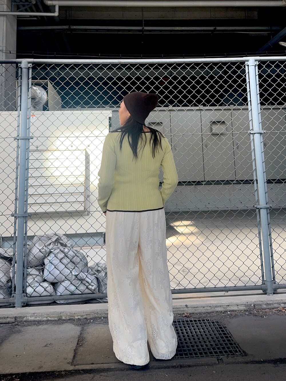 グリーン系のニット/セーター、ホワイト系のその他パンツ、ブラウン系のニットキャップ/ビーニーを着用したレディースの冬コーディネートの2枚目の写真