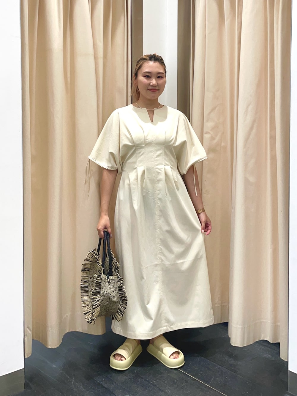 ホワイト系のワンピース、イエロー系のサンダル、ブラック系のハンドバッグを着用したレディースの春コーディネートの2枚目の写真