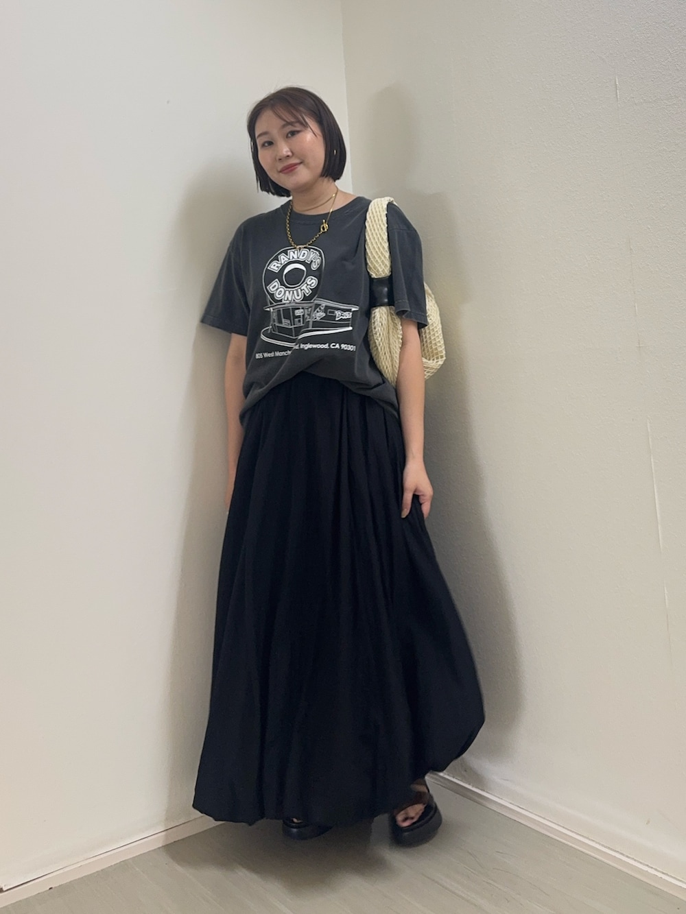 グレー系のTシャツ/カットソー、ブラック系のスカート、ホワイト系のショルダーバッグを着用したレディースの春コーディネートの2枚目の写真