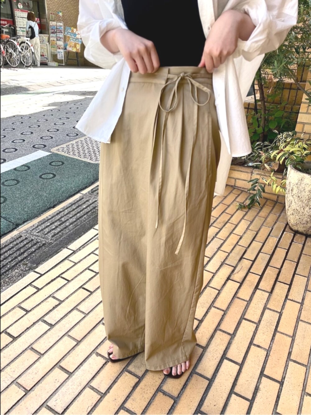 ベージュ系のその他パンツ、ホワイト系のシャツ/ブラウスを着用したレディースの夏コーディネートの2枚目の写真