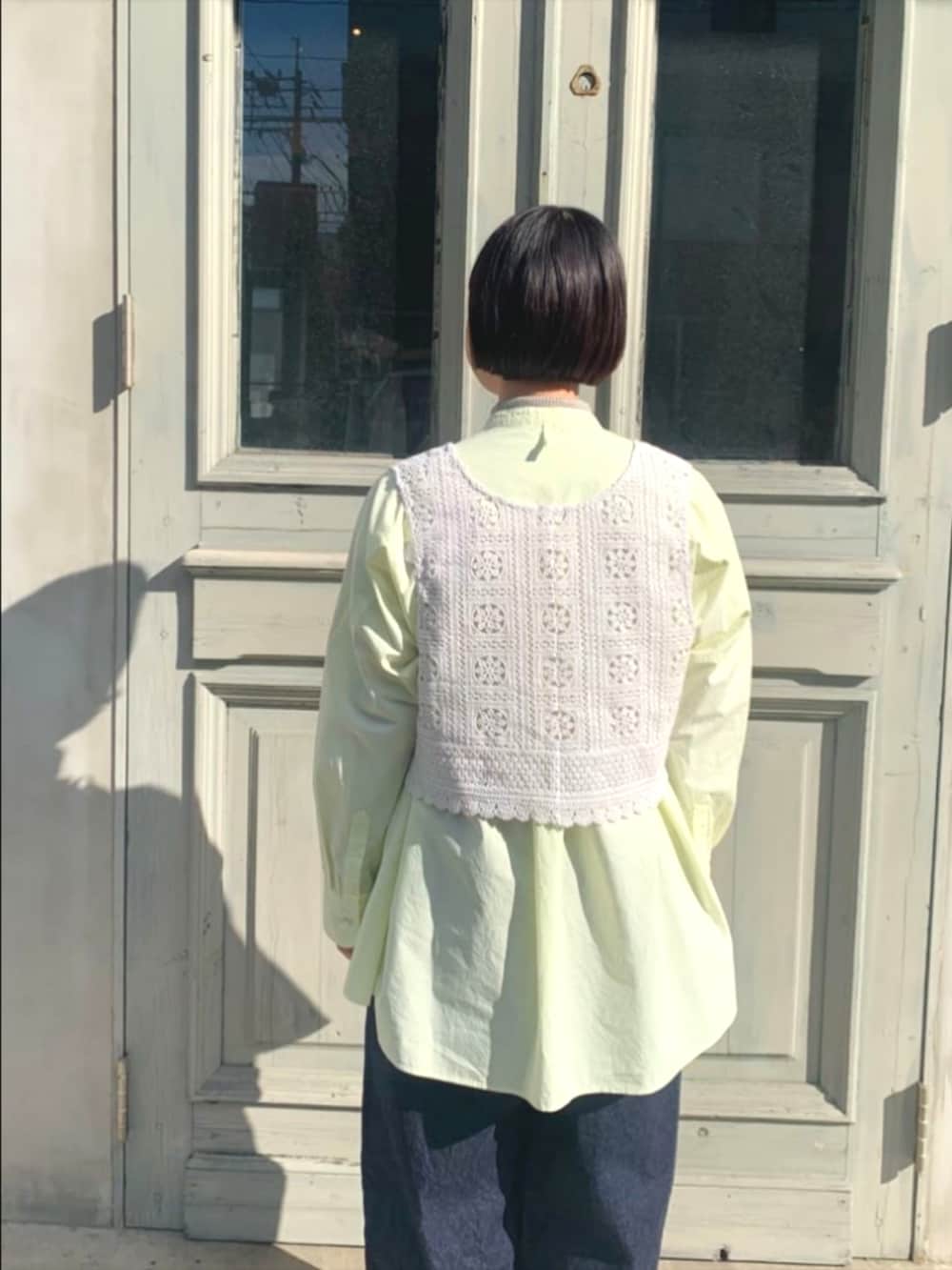 イエロー系のシャツ/ブラウス、ブルー系のデニムパンツ、ホワイト系のベストを着用したレディースの冬コーディネートの2枚目の写真