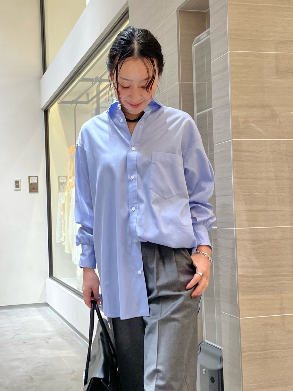 ブラック系のボストンバッグ、ブラウン系のサンダル、グレー系のスラックスを着用したレディースの冬コーディネートの2枚目の写真