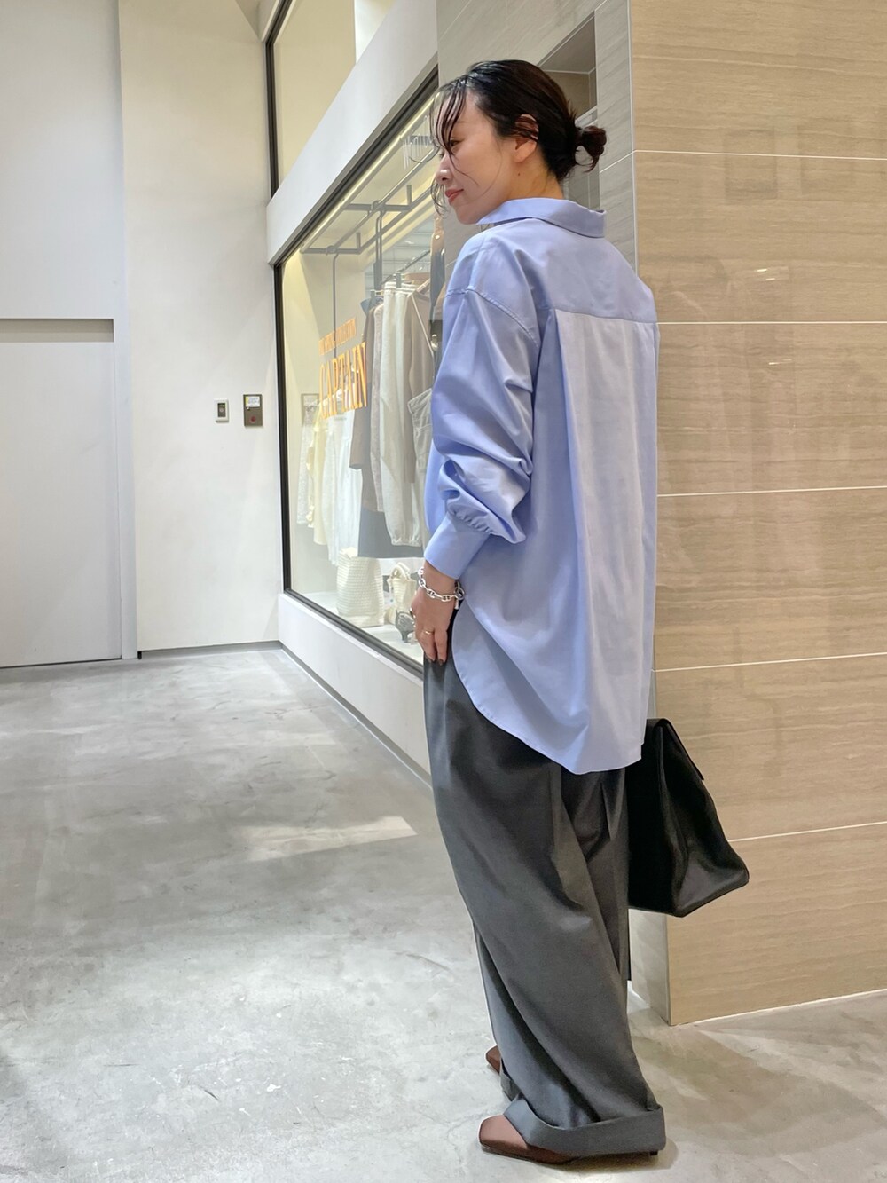 ブラック系のボストンバッグ、ブラウン系のサンダル、グレー系のスラックスを着用したレディースの冬コーディネートの4枚目の写真