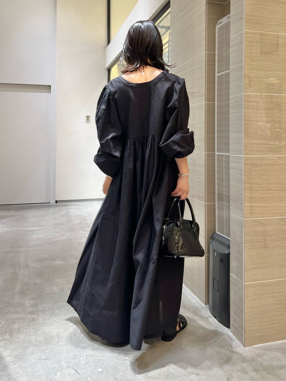 ブラック系のワンピース、ブラック系のサンダル、ブラック系のボストンバッグを着用したレディースの春コーディネートの4枚目の写真