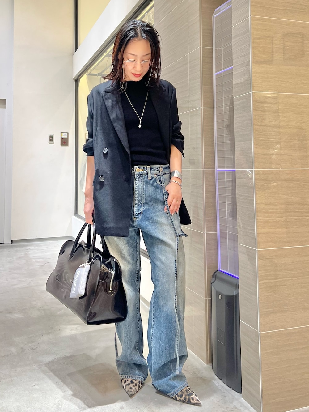 ブルー系のデニムパンツ、ブラック系のニット/セーター、イエロー系のパンプスを着用したレディースの春コーディネートの5枚目の写真