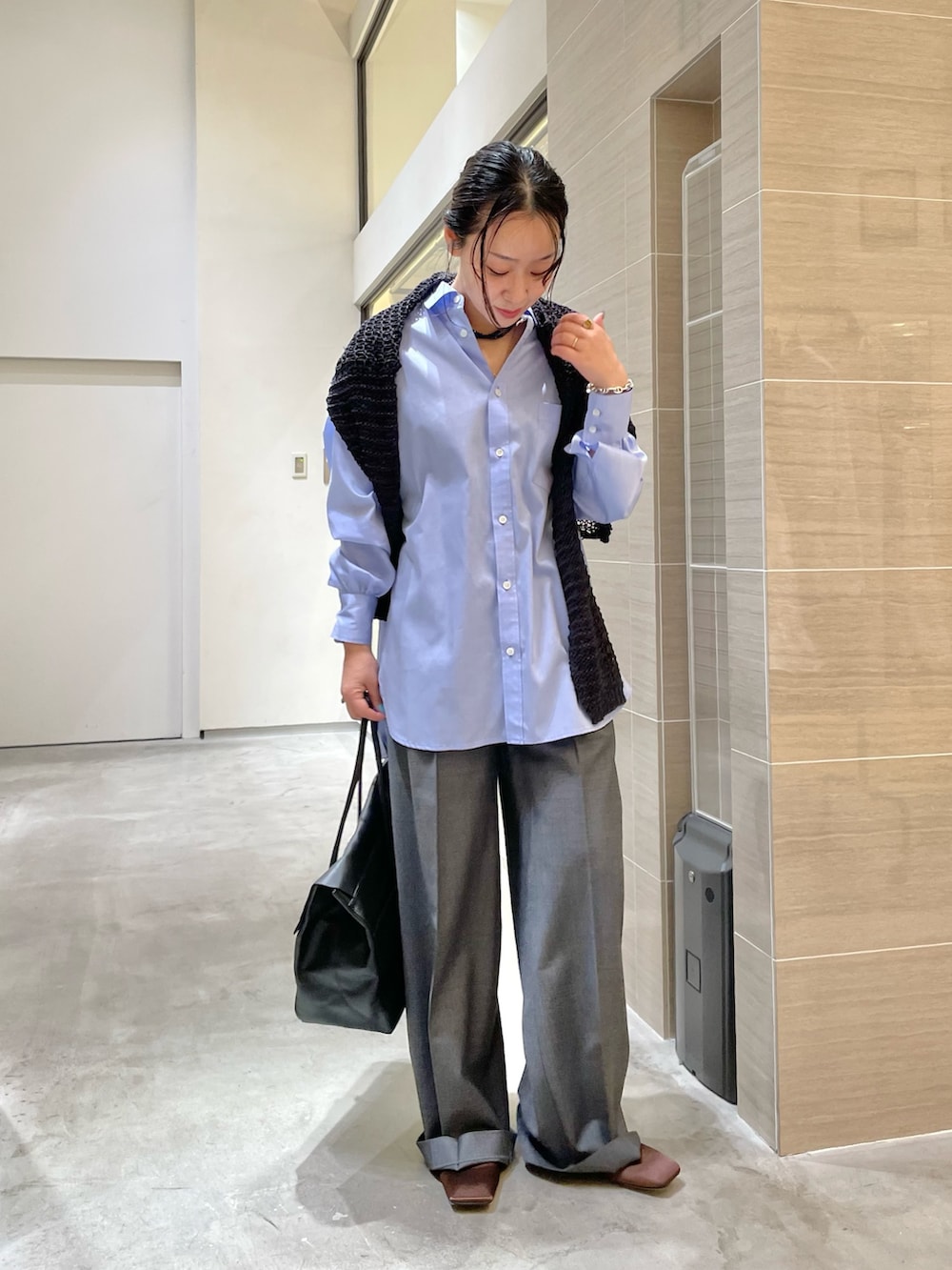 ブラック系のボストンバッグ、ブラウン系のサンダル、グレー系のスラックスを着用したレディースの冬コーディネートの5枚目の写真