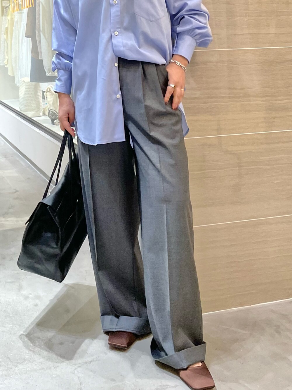 ブラック系のボストンバッグ、ブラウン系のサンダル、グレー系のスラックスを着用したレディースの冬コーディネートの3枚目の写真