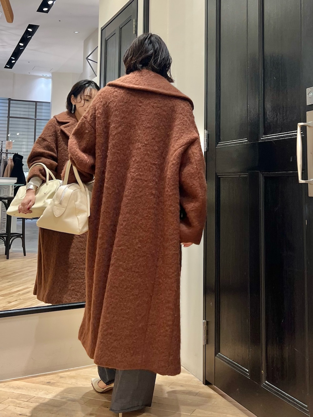 グレー系のスラックス、ホワイト系のTシャツ/カットソー、ベージュ系のトートバッグを着用したレディースの秋コーディネートの6枚目の写真