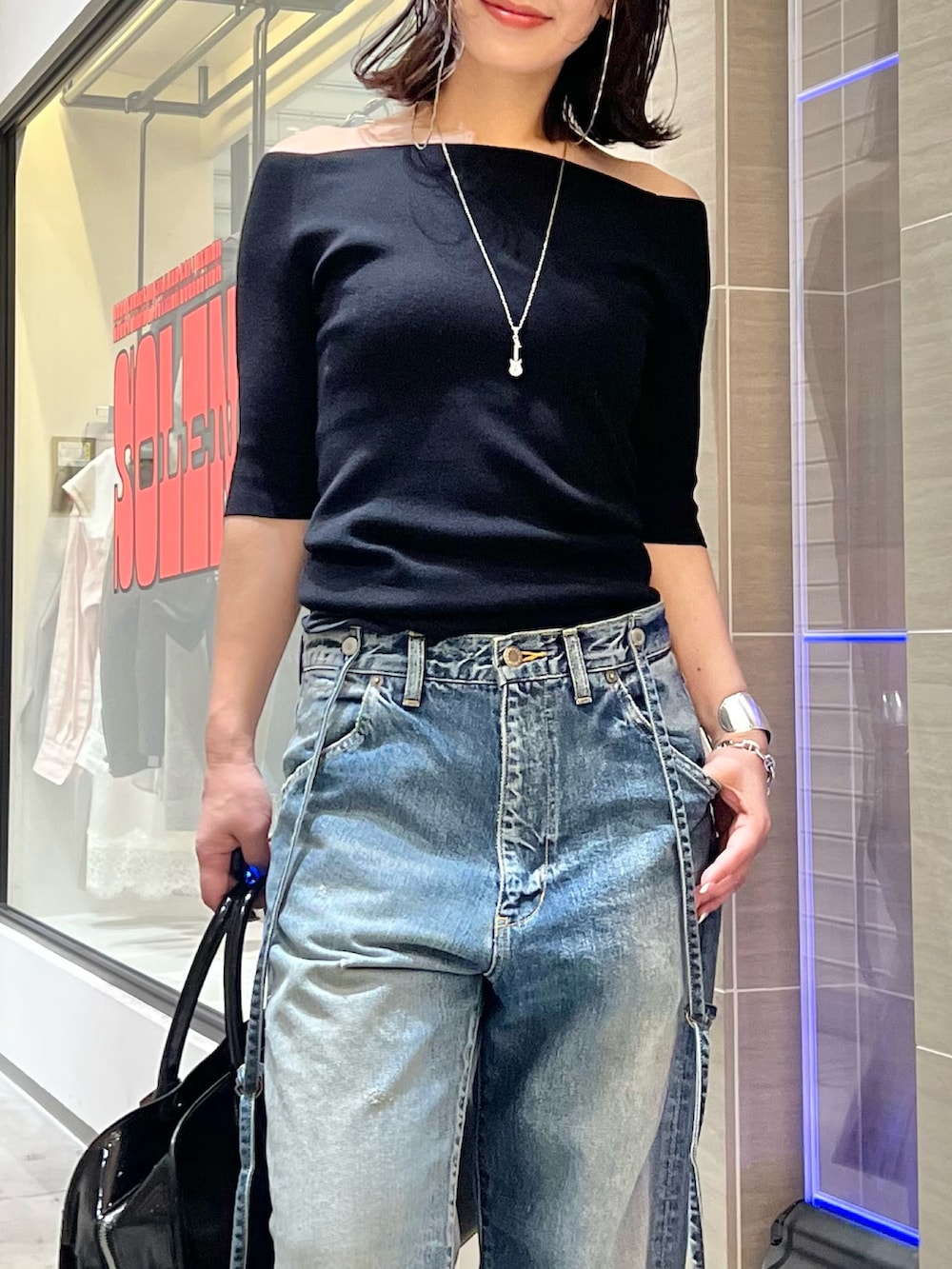 ブルー系のデニムパンツ、ブラック系のニット/セーター、イエロー系のパンプスを着用したレディースの春コーディネートの2枚目の写真