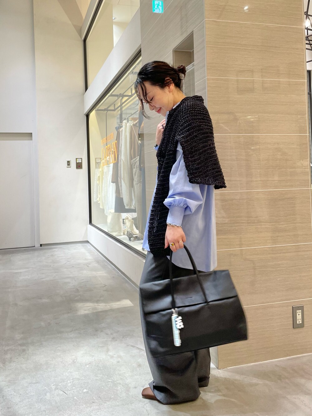 ブラック系のボストンバッグ、ブラウン系のサンダル、グレー系のスラックスを着用したレディースの冬コーディネートの6枚目の写真