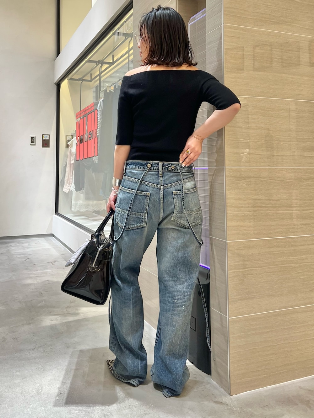 ブルー系のデニムパンツ、ブラック系のニット/セーター、イエロー系のパンプスを着用したレディースの春コーディネートの4枚目の写真