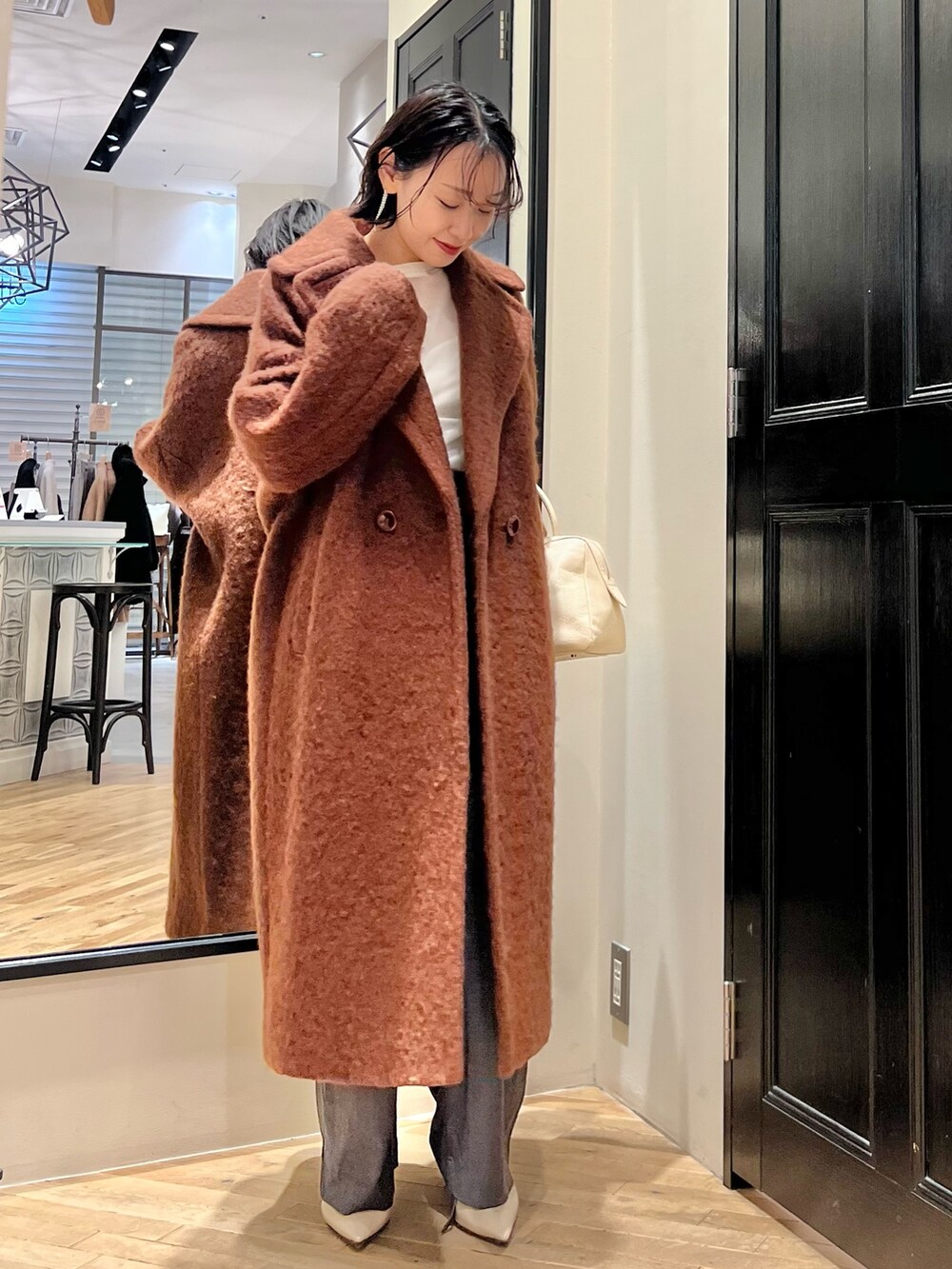 グレー系のスラックス、ホワイト系のTシャツ/カットソー、ベージュ系のトートバッグを着用したレディースの秋コーディネートの2枚目の写真