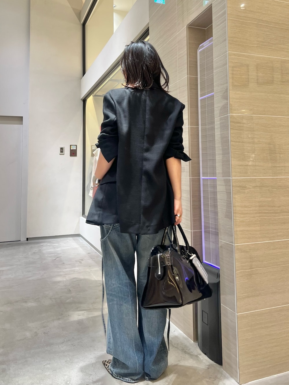 ブルー系のデニムパンツ、ブラック系のニット/セーター、イエロー系のパンプスを着用したレディースの春コーディネートの6枚目の写真