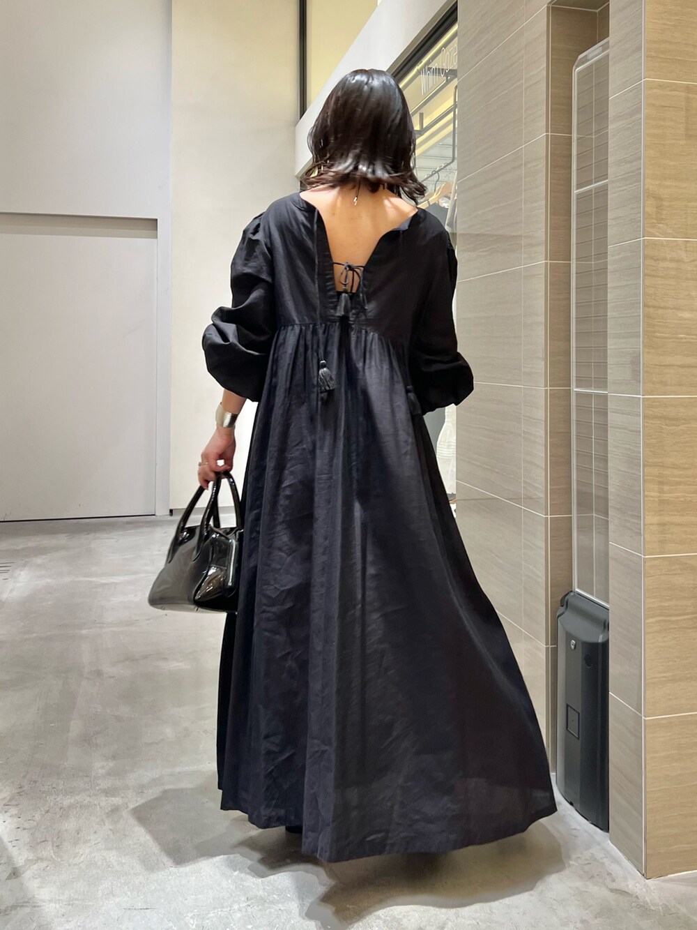 ブラック系のワンピース、ブラック系のサンダル、ブラック系のボストンバッグを着用したレディースの春コーディネートの2枚目の写真