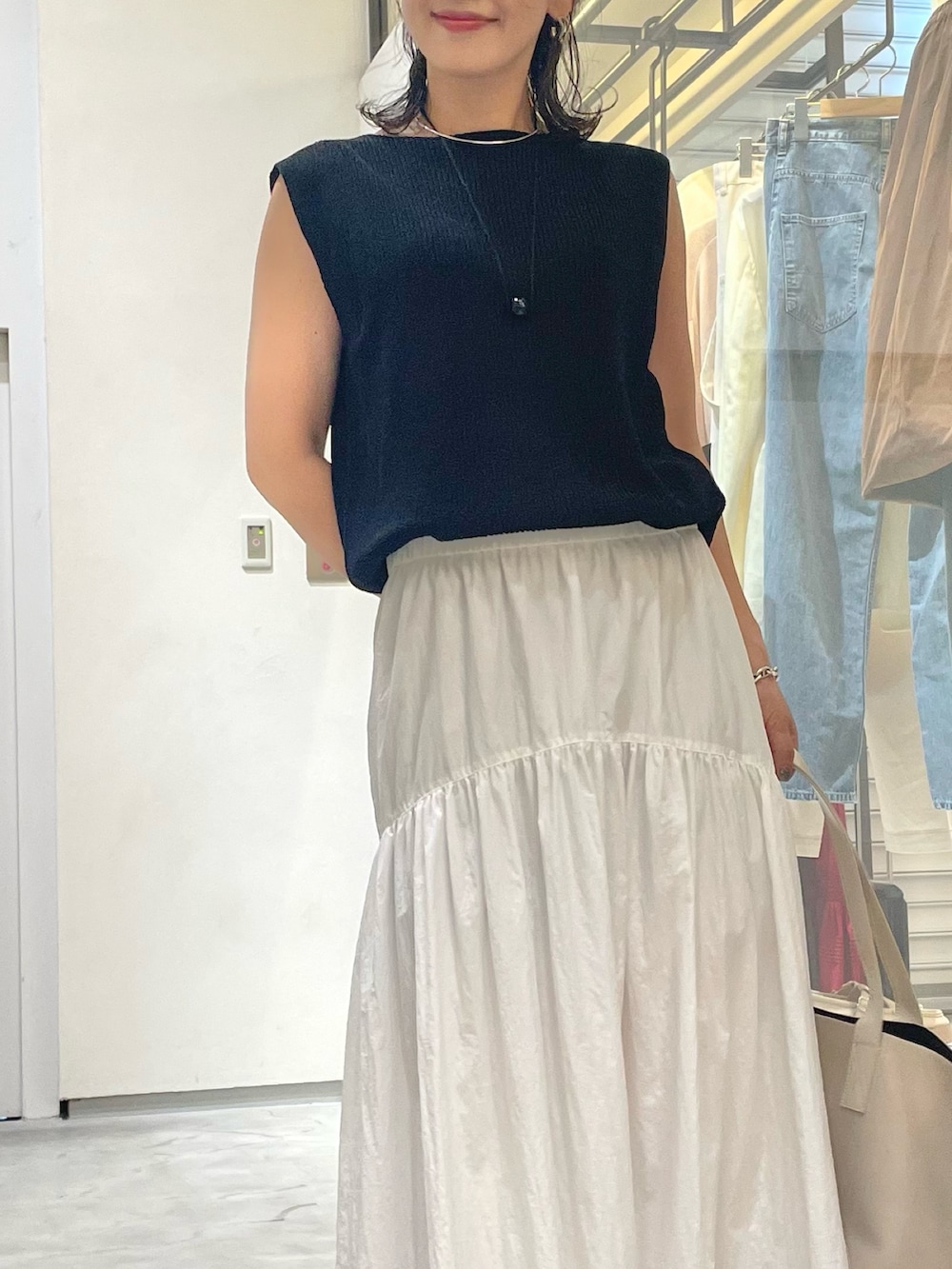 ホワイト系のスカート、ブラック系のニット/セーター、ブラック系のサンダルを着用したレディースの夏コーディネートの4枚目の写真