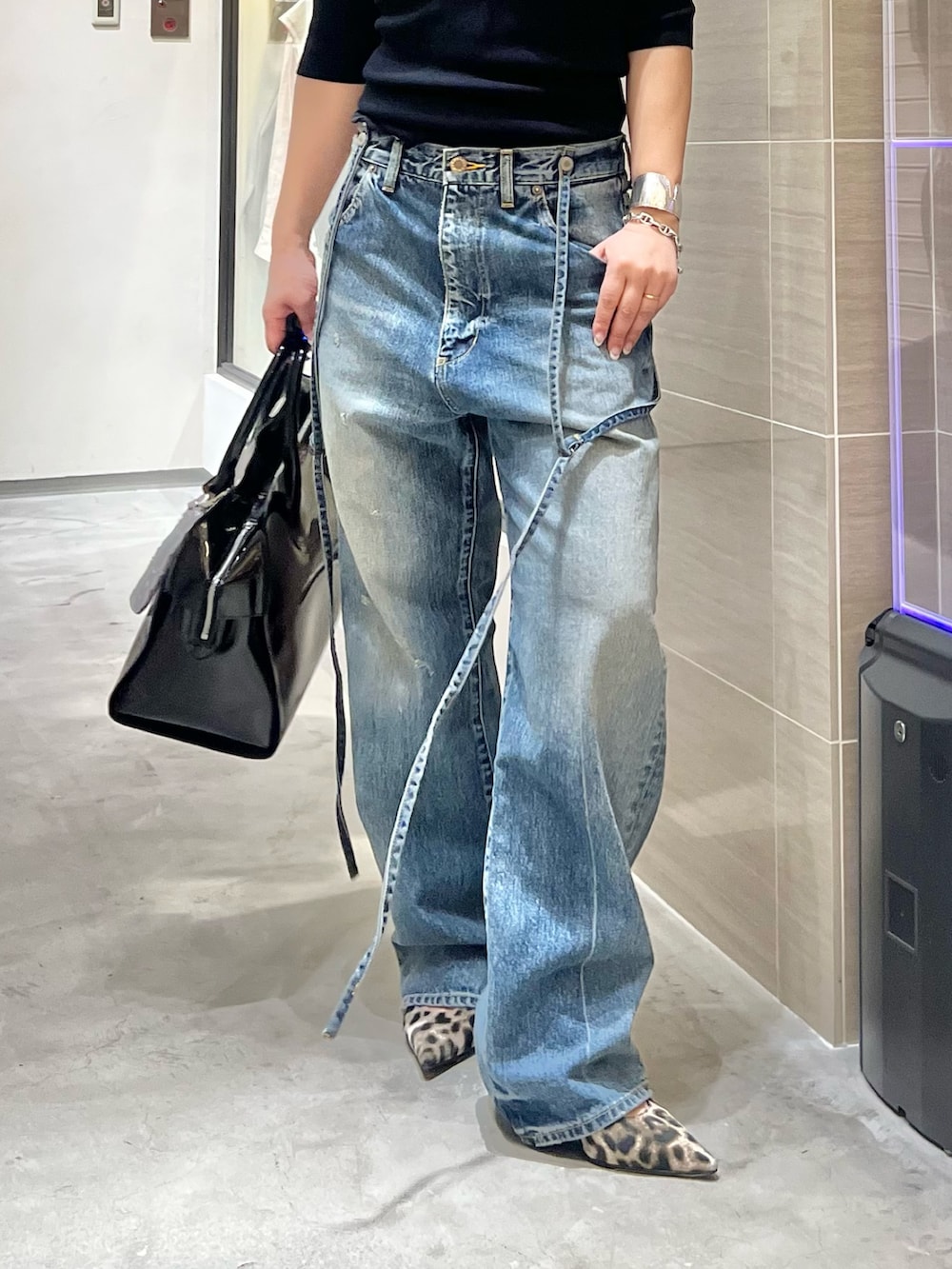 ブルー系のデニムパンツ、ブラック系のニット/セーター、イエロー系のパンプスを着用したレディースの春コーディネートの3枚目の写真