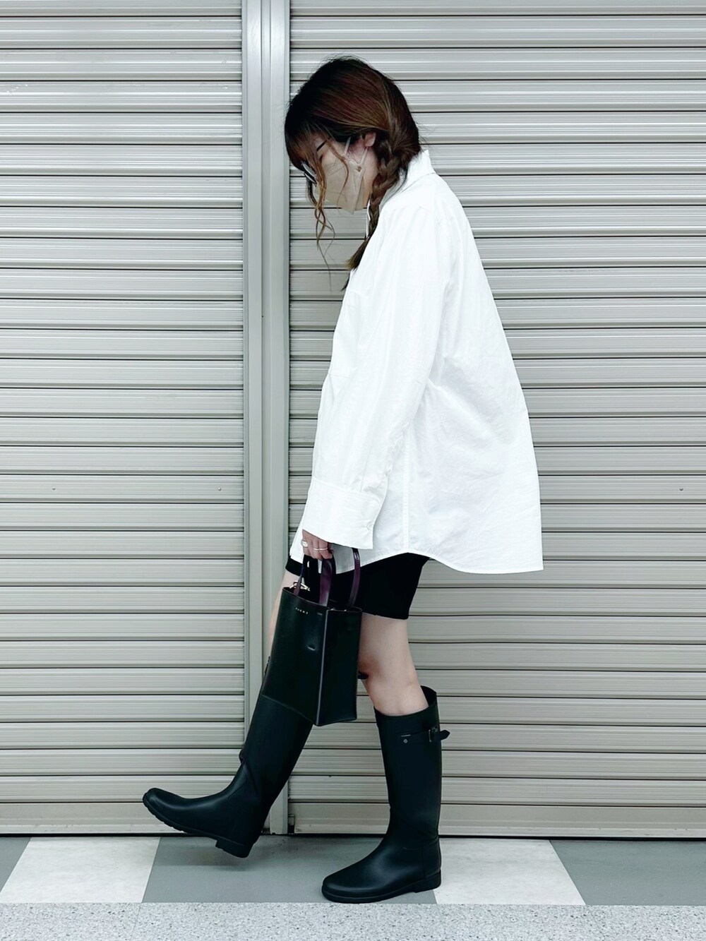 ブラック系のレインシューズ、ブラック系のショルダーバッグ、ホワイト系のシャツ/ブラウスを着用したレディースの春コーディネートの2枚目の写真