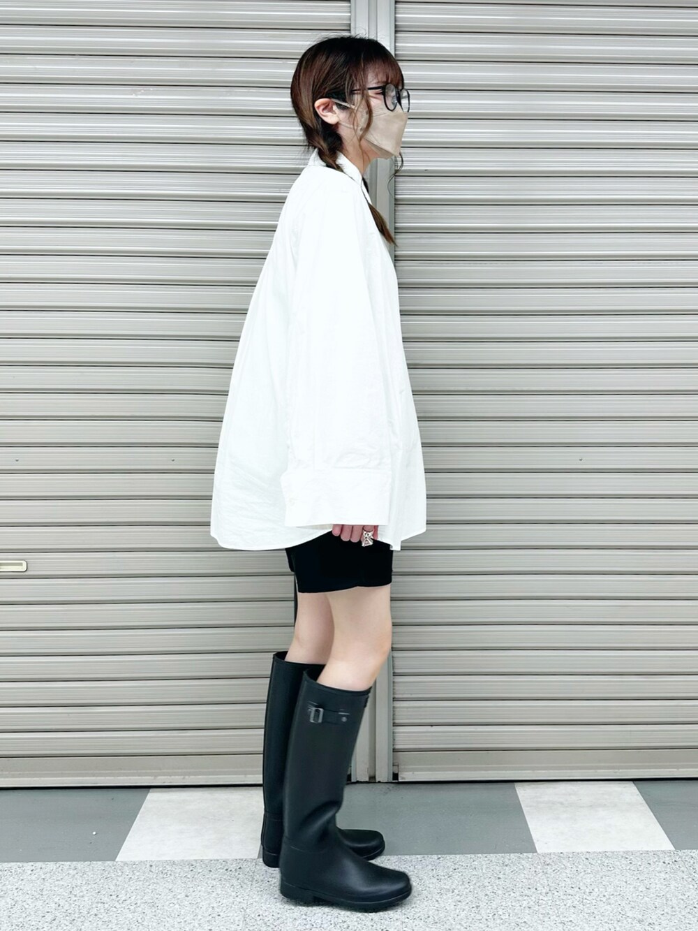 ブラック系のレインシューズ、ブラック系のショルダーバッグ、ホワイト系のシャツ/ブラウスを着用したレディースの春コーディネートの3枚目の写真