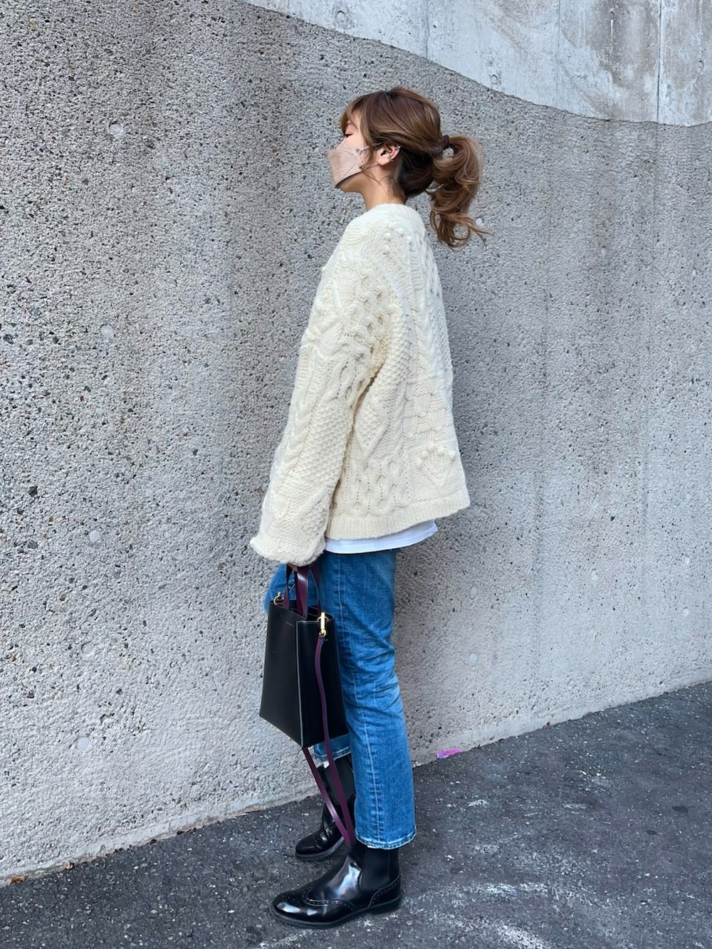 ホワイト系のニット/セーター、ブルー系のデニムパンツ、ブラック系のショルダーバッグを着用したレディースの冬コーディネートの3枚目の写真