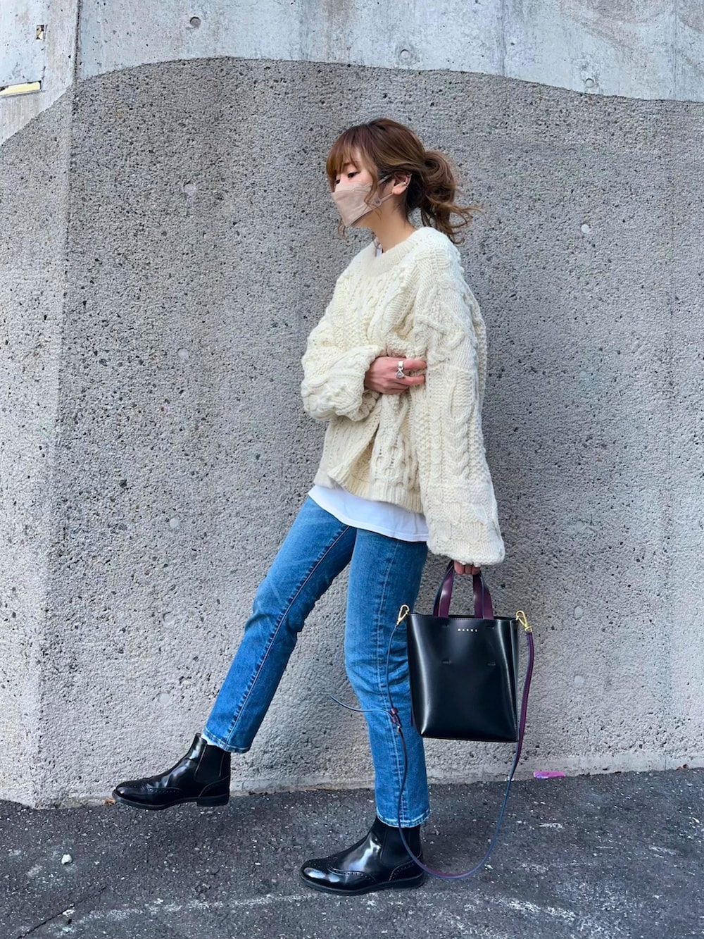 ホワイト系のニット/セーター、ブルー系のデニムパンツ、ブラック系のショルダーバッグを着用したレディースの冬コーディネートの2枚目の写真