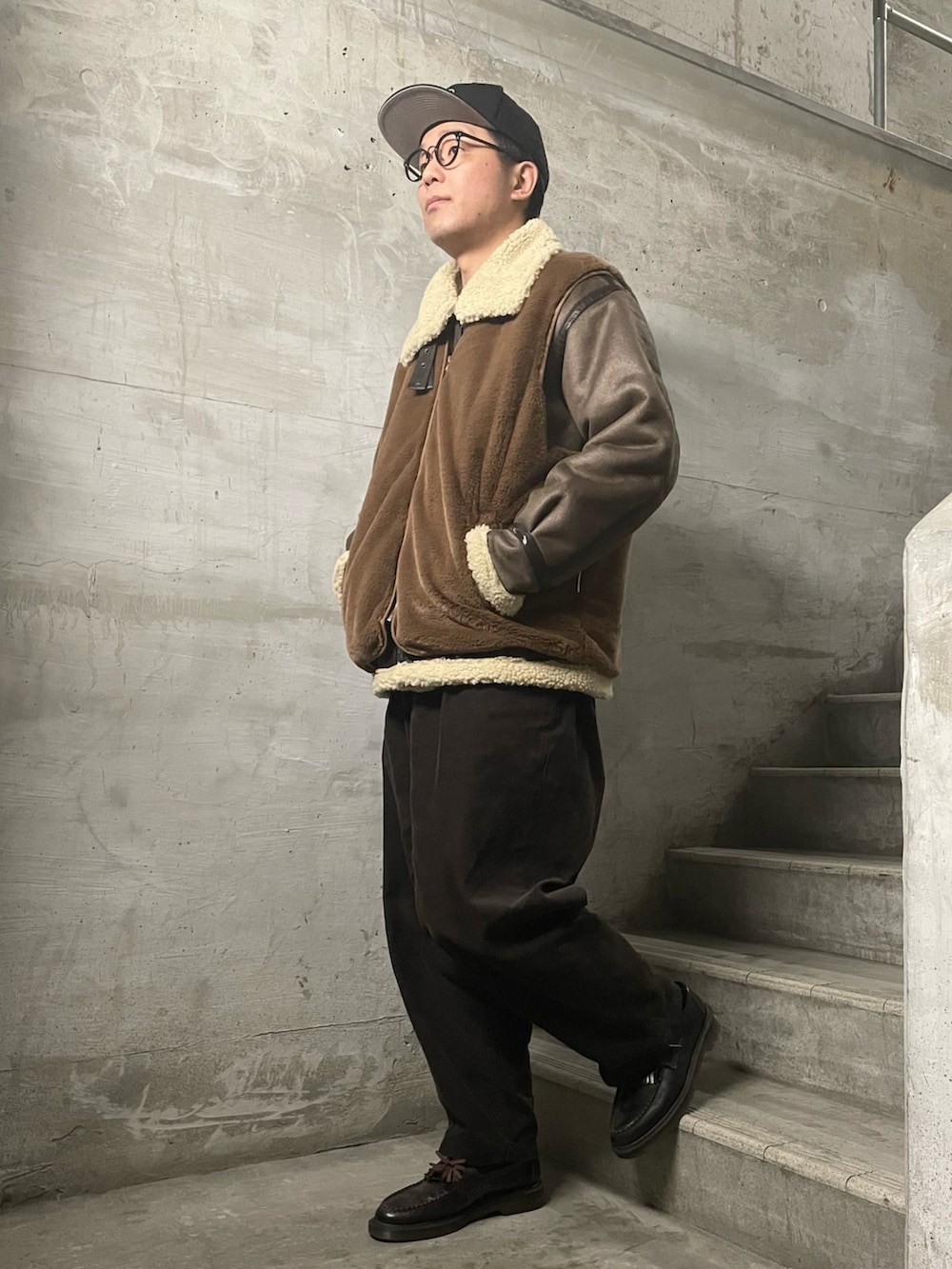 ブラウン系のムートンコート、ブラウン系のベスト、ブラウン系のその他パンツを着用したメンズの冬コーディネートの4枚目の写真
