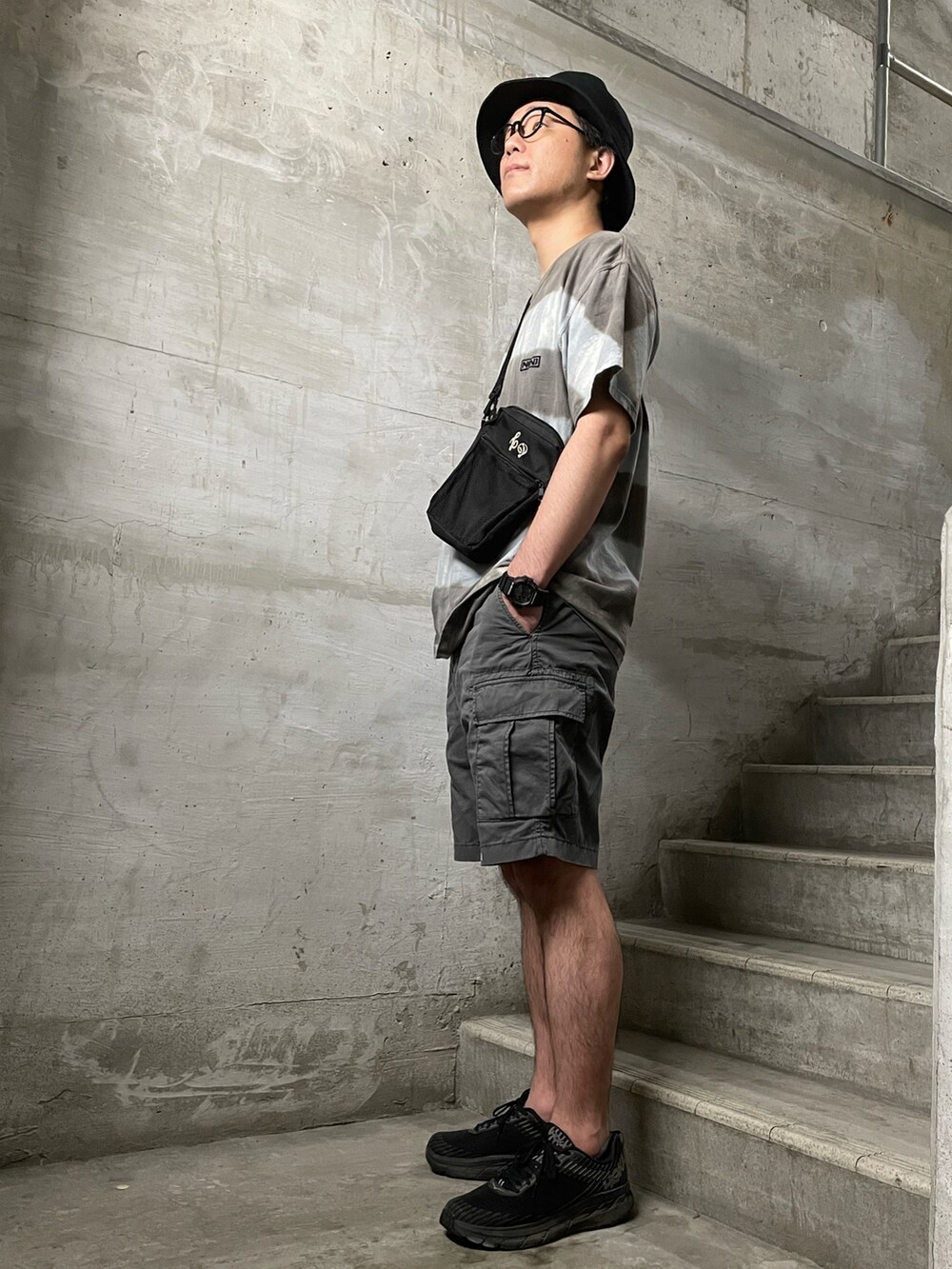 ブラック系のバックパック/リュック、グレー系のTシャツ/カットソー、グレー系のカーゴパンツを着用したメンズの夏コーディネートの2枚目の写真