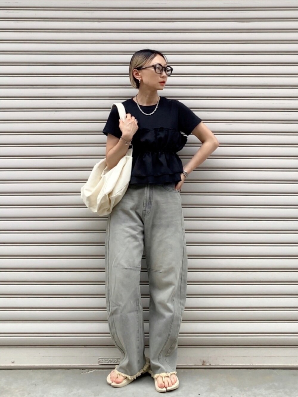 ブラック系のTシャツ/カットソー、グレー系のデニムパンツ、ホワイト系のショルダーバッグを着用したレディースの夏コーディネートの2枚目の写真
