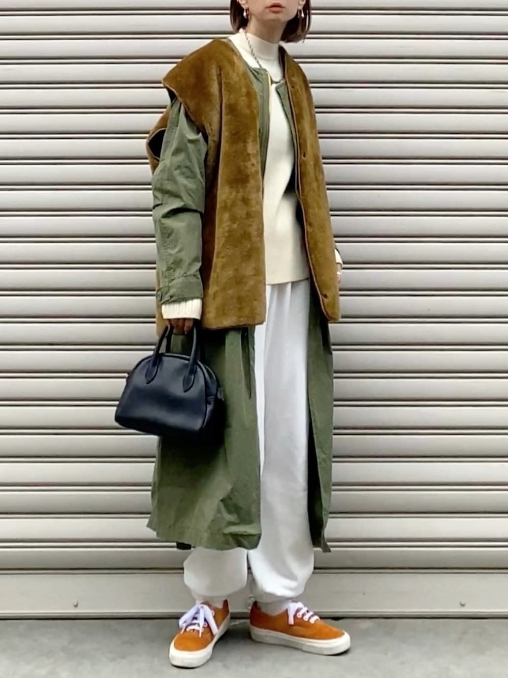 ブラウン系のベスト、グリーン系のモッズコート、ベージュ系のスウェットパンツを着用したレディースの冬コーディネートの2枚目の写真