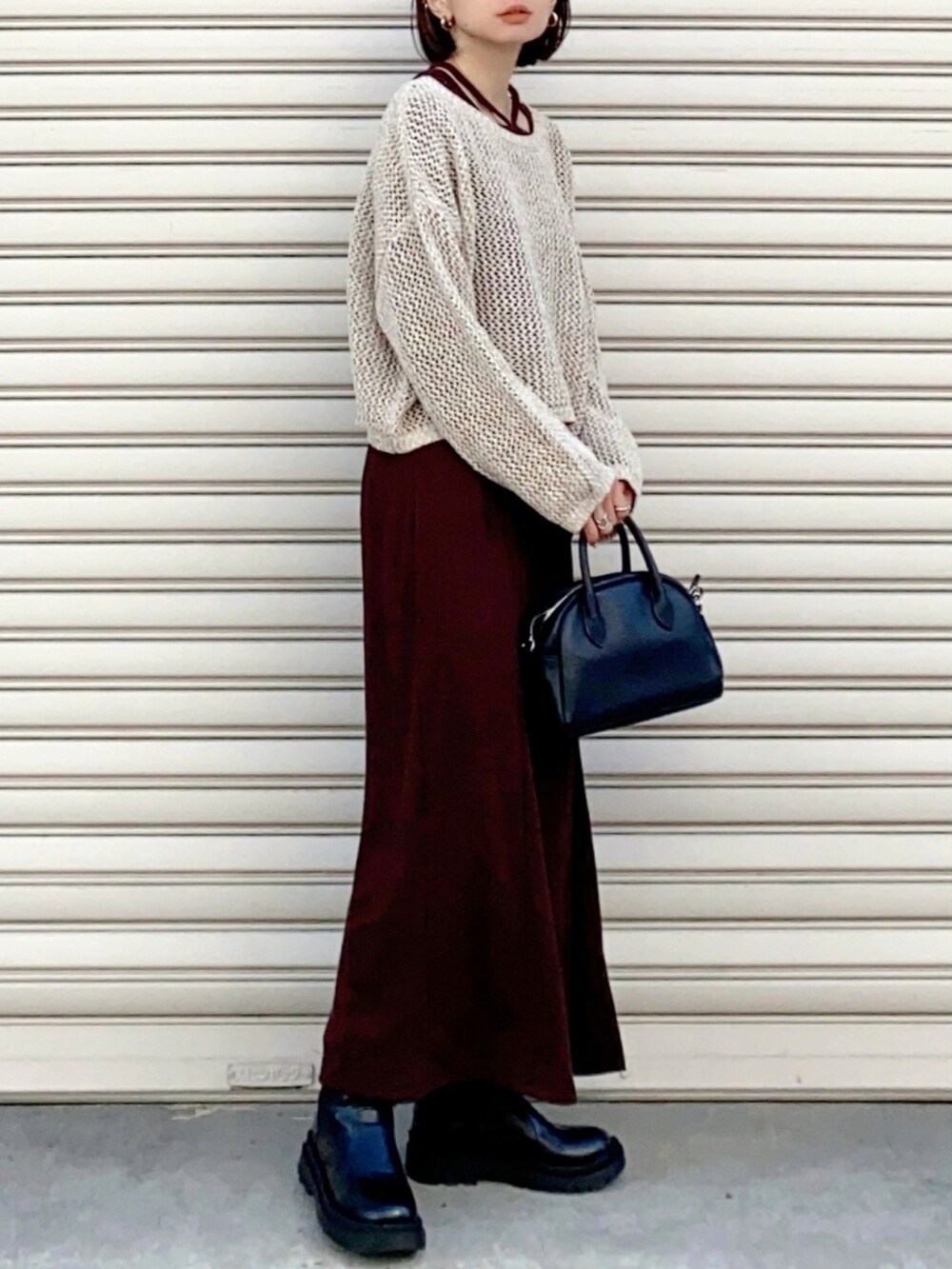 ベージュ系のニット/セーター、ブラック系のショルダーバッグ、ブラック系のワンピースを着用したレディースの春コーディネートの2枚目の写真