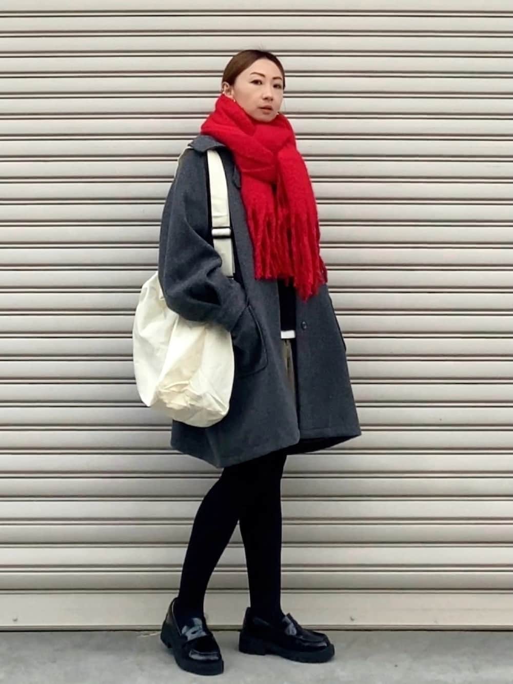 グレー系のステンカラーコート、ホワイト系のショルダーバッグ、ブラウン系のパンツを着用したレディースの冬コーディネートの3枚目の写真