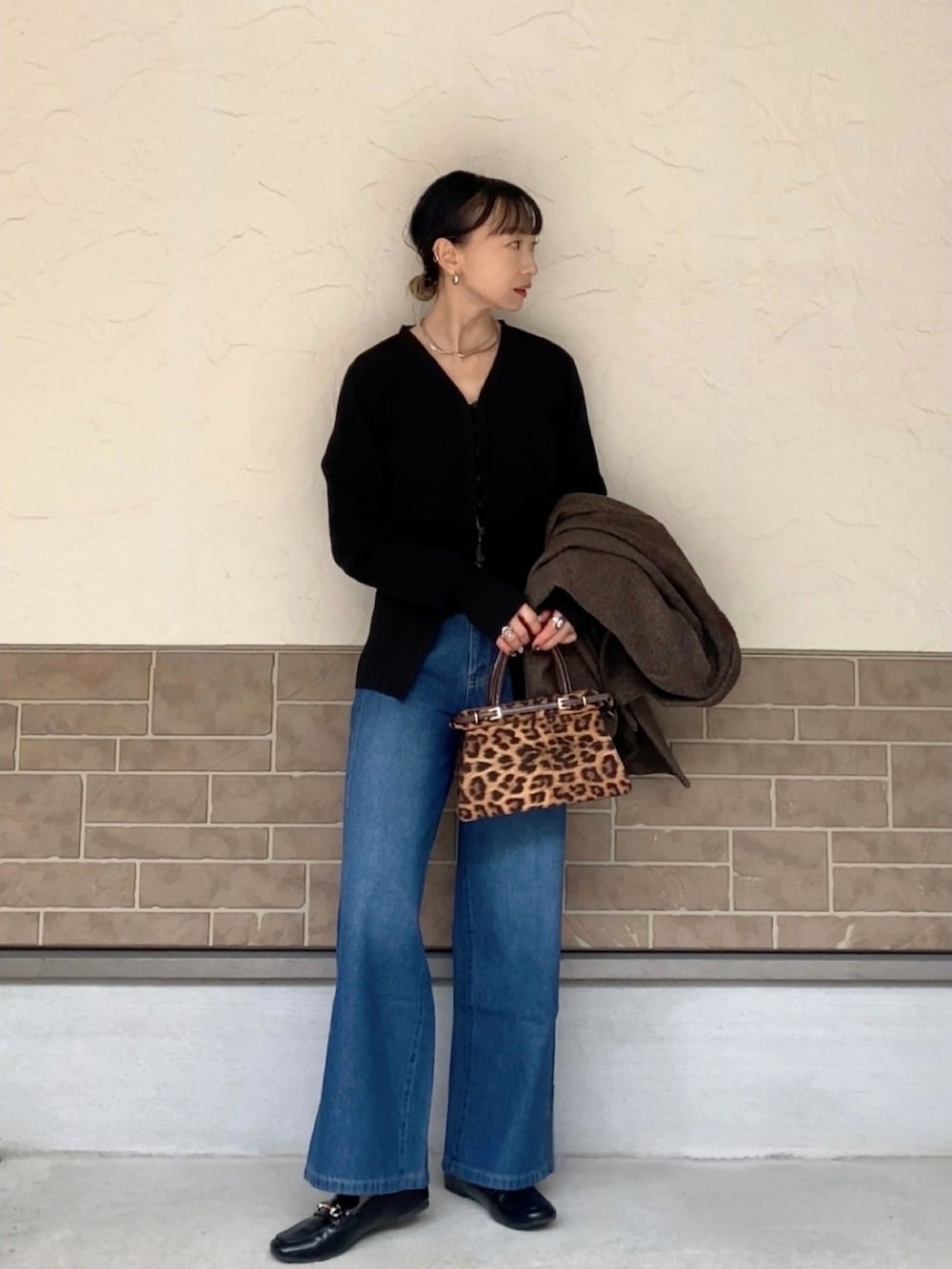 ブルー系のデニムパンツ、ブラック系のカーディガン/ボレロ、ブラウン系のバッグを着用したレディースの冬コーディネートの3枚目の写真