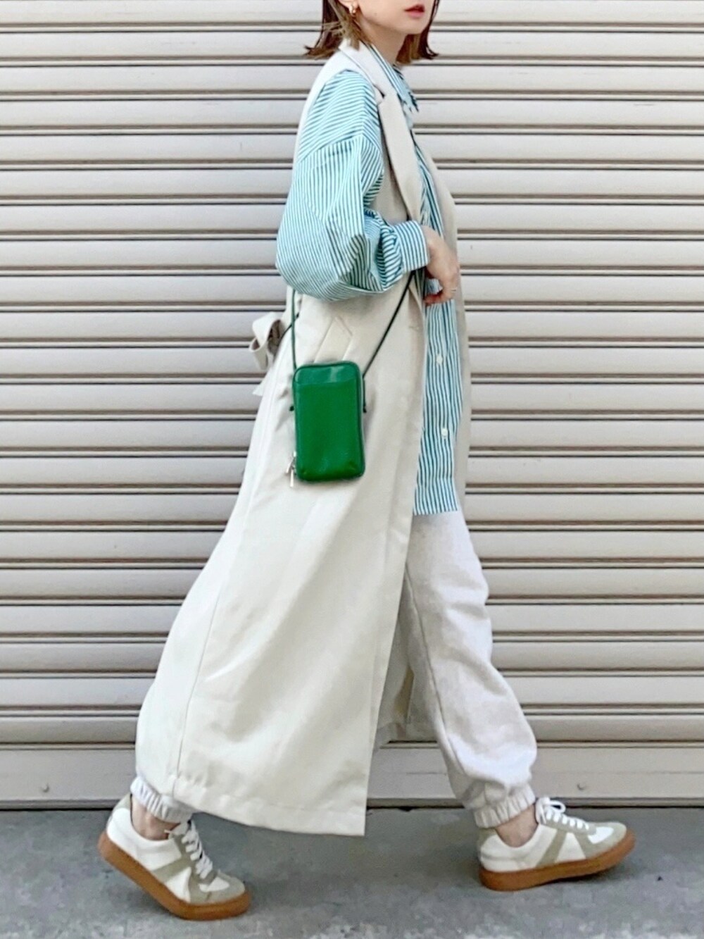 ホワイト系のベスト、グリーン系のシャツ/ブラウス、ホワイト系のスニーカーを着用したレディースの春コーディネートの2枚目の写真