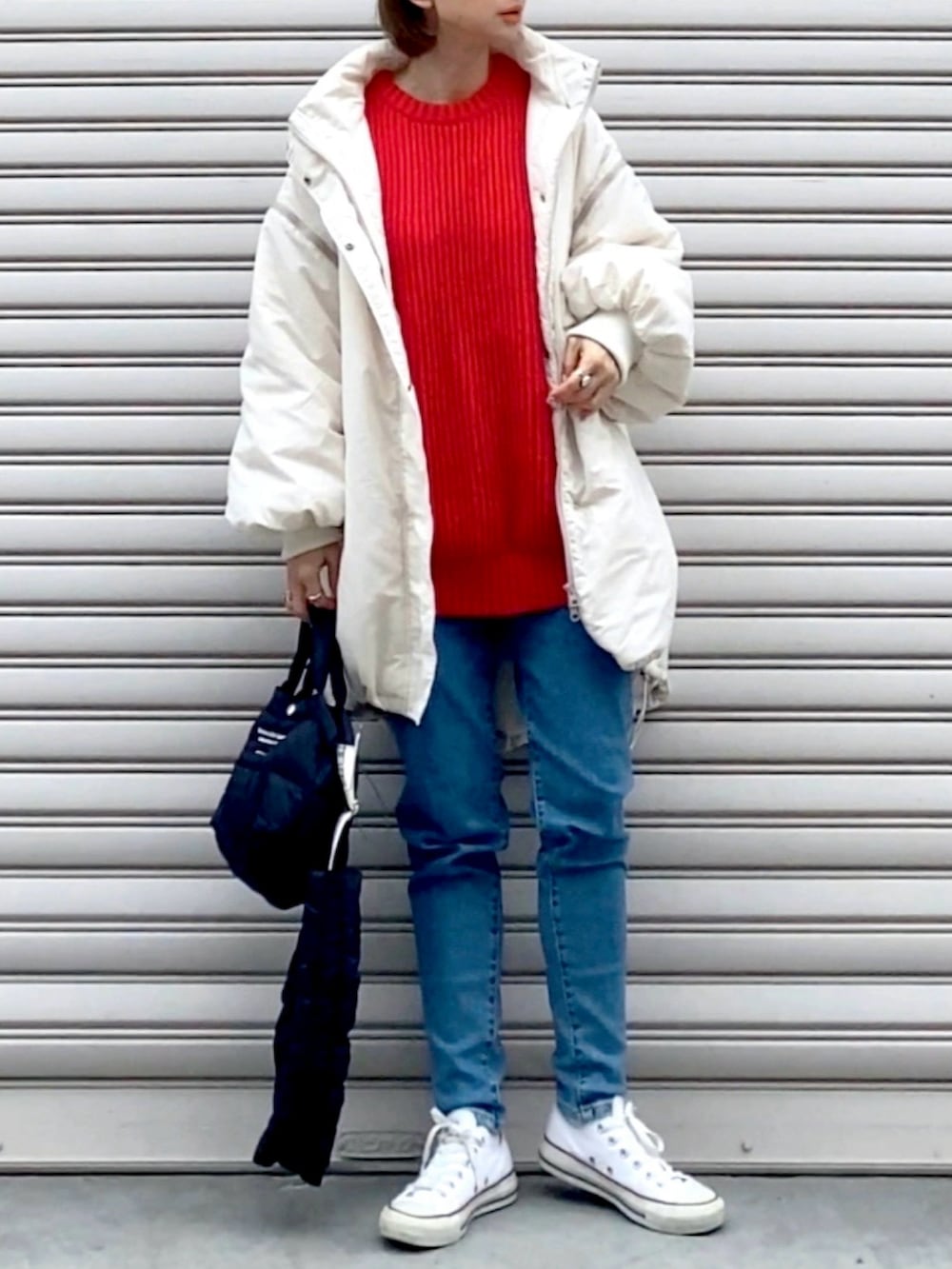 レッド系のニット/セーター、ブラック系のショルダーバッグ、ブルー系のデニムパンツを着用したレディースの冬コーディネートの2枚目の写真