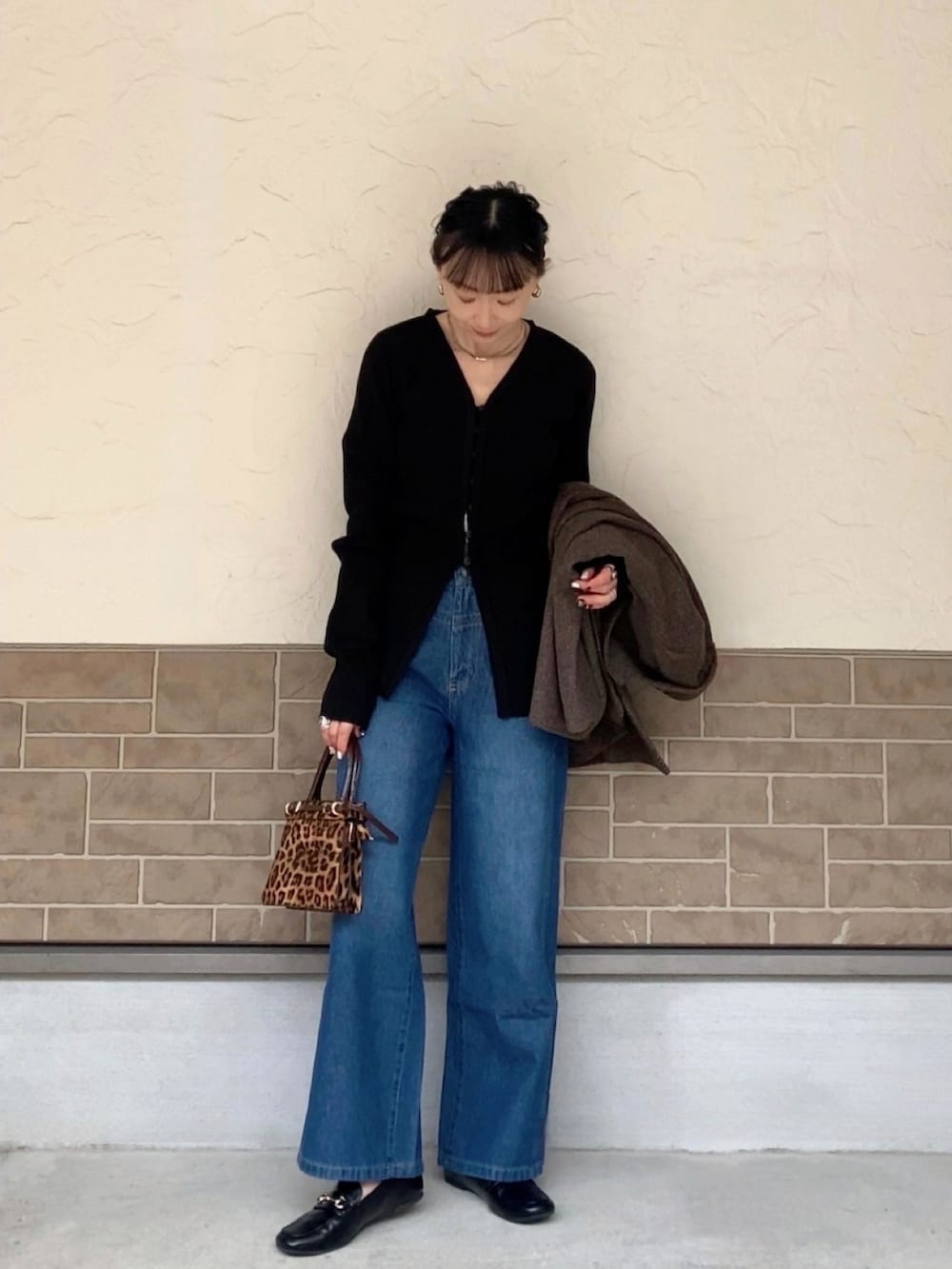 ブルー系のデニムパンツ、ブラック系のカーディガン/ボレロ、ブラウン系のバッグを着用したレディースの冬コーディネートの2枚目の写真