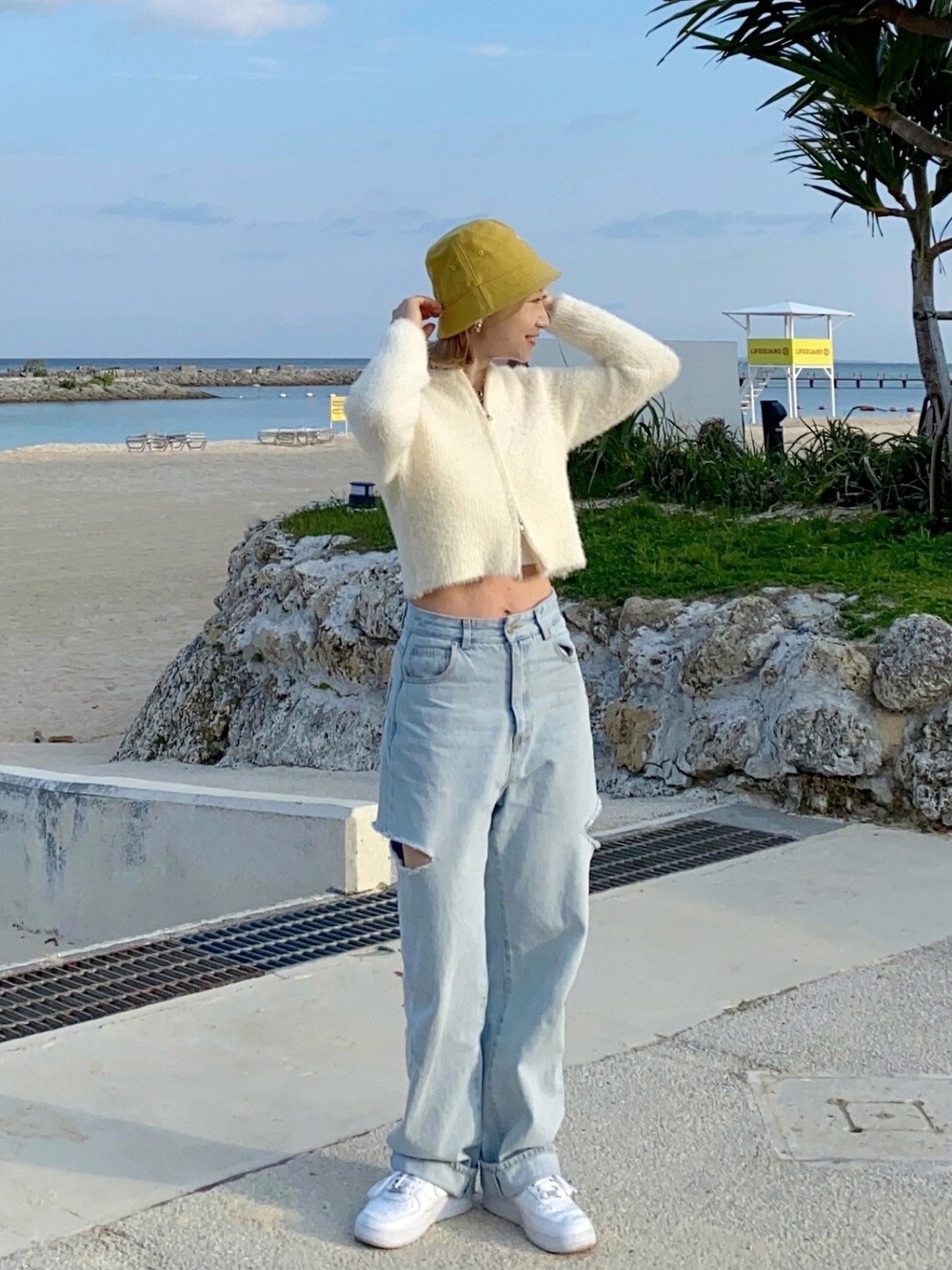 ホワイト系のニット/セーター、ブルー系のデニムパンツ、ホワイト系のスニーカーを着用したレディースの春コーディネートの2枚目の写真