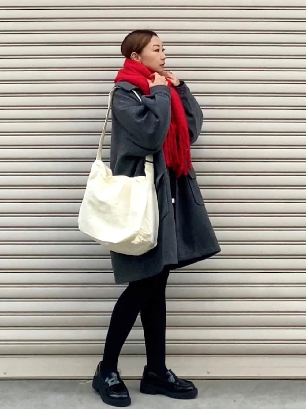 グレー系のステンカラーコート、ホワイト系のショルダーバッグ、ブラウン系のパンツを着用したレディースの冬コーディネートの2枚目の写真