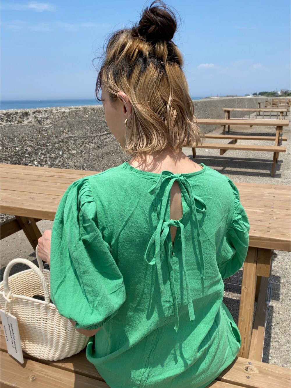 グリーン系のワンピース、ホワイト系のハンドバッグ、ホワイト系のタンクトップを着用したレディースの春コーディネートの2枚目の写真