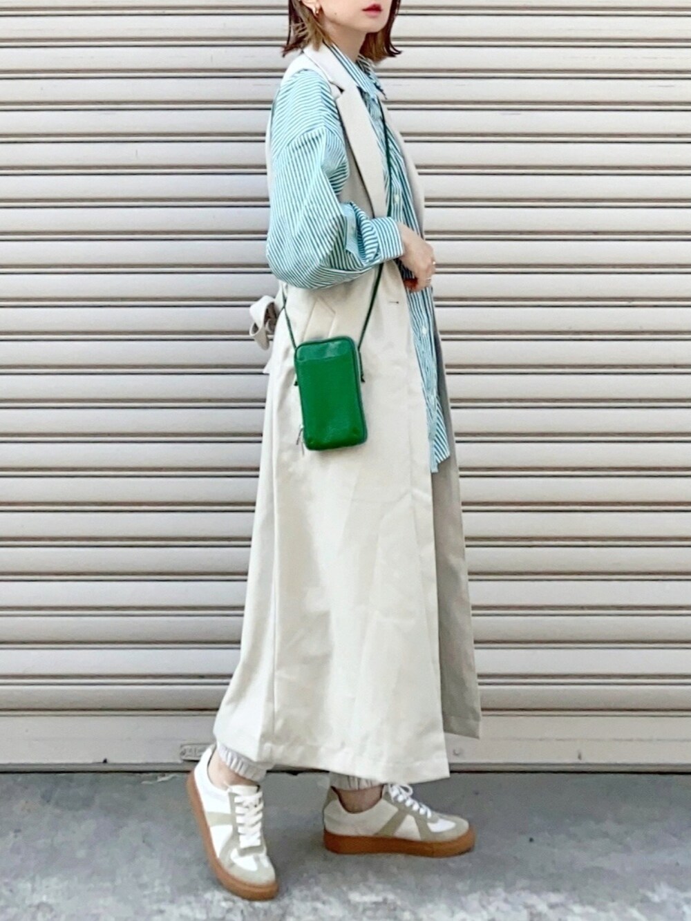 ホワイト系のベスト、グリーン系のシャツ/ブラウス、ホワイト系のスニーカーを着用したレディースの春コーディネートの3枚目の写真