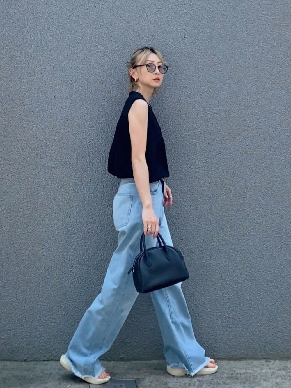 ブラック系のシャツ/ブラウス、ブルー系のデニムパンツ、ブラック系のボストンバッグを着用したレディースの夏コーディネートの2枚目の写真