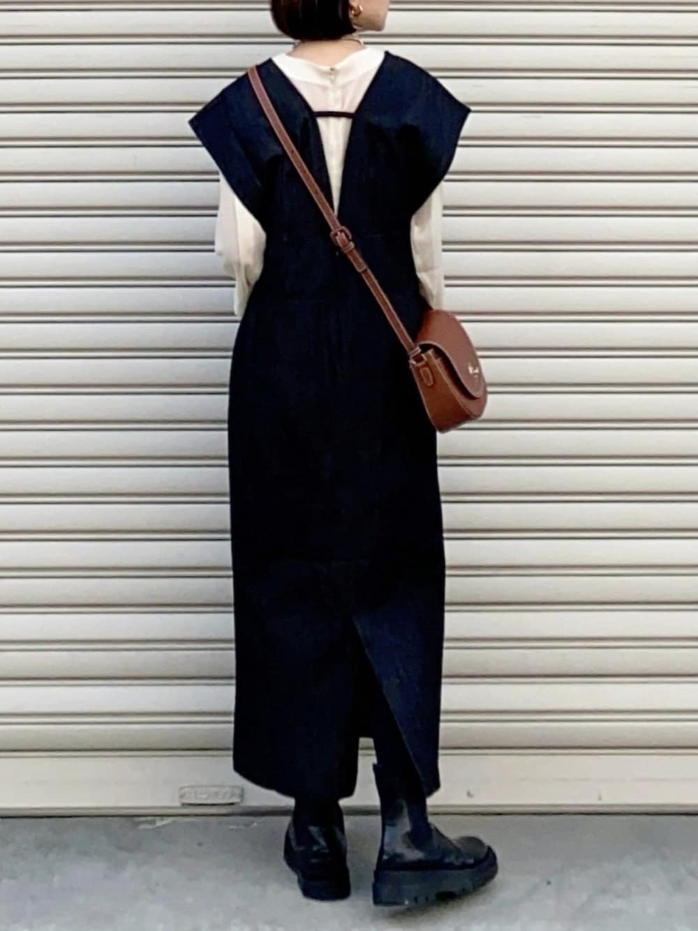 ブラウン系のショルダーバッグ、ブラック系のジャンパースカート、ブラック系のブーツを着用したレディースの冬コーディネートの3枚目の写真