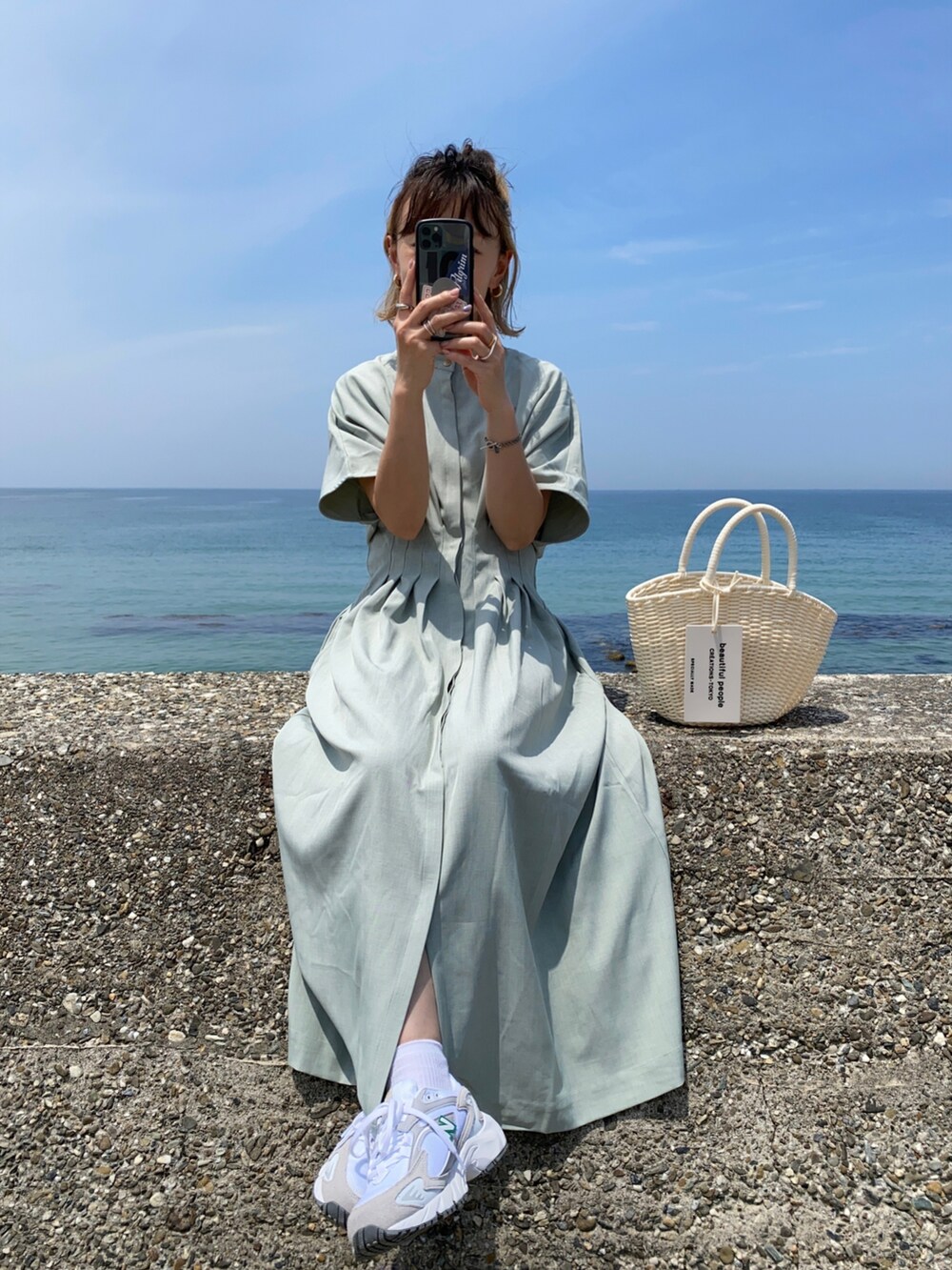 グリーン系のワンピース、ホワイト系のハンドバッグ、ホワイト系のスニーカーを着用したレディースの春コーディネートの2枚目の写真