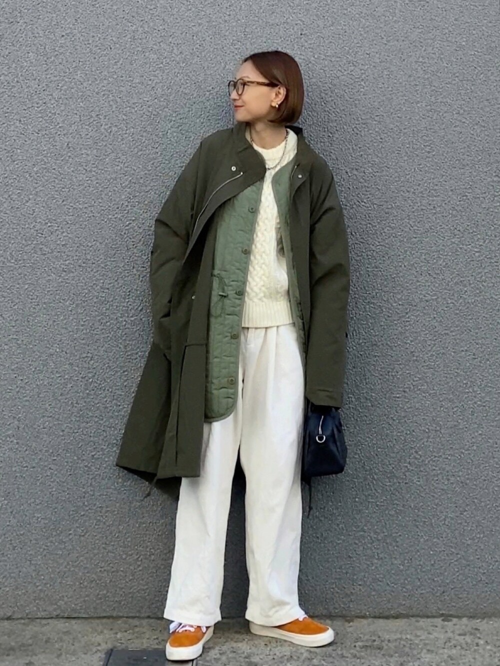 グリーン系のモッズコート、ホワイト系のチノパンツ、オレンジ系のスニーカーを着用したレディースの秋コーディネートの2枚目の写真