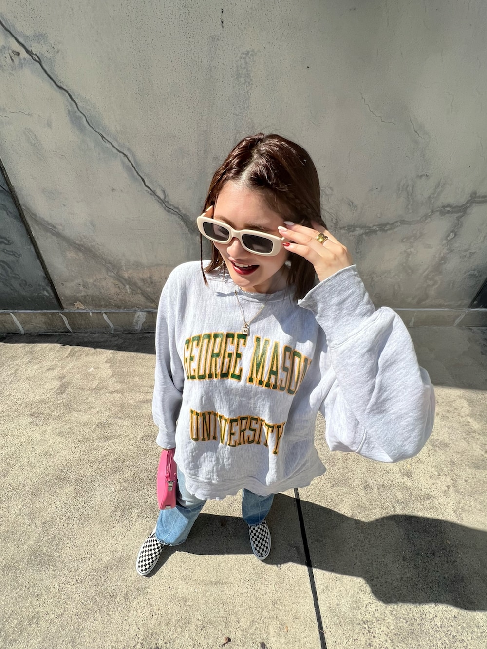 グレー系のスウェット、ブルー系のデニムパンツ、ブラック系のスニーカーを着用したレディースの秋コーディネートの2枚目の写真